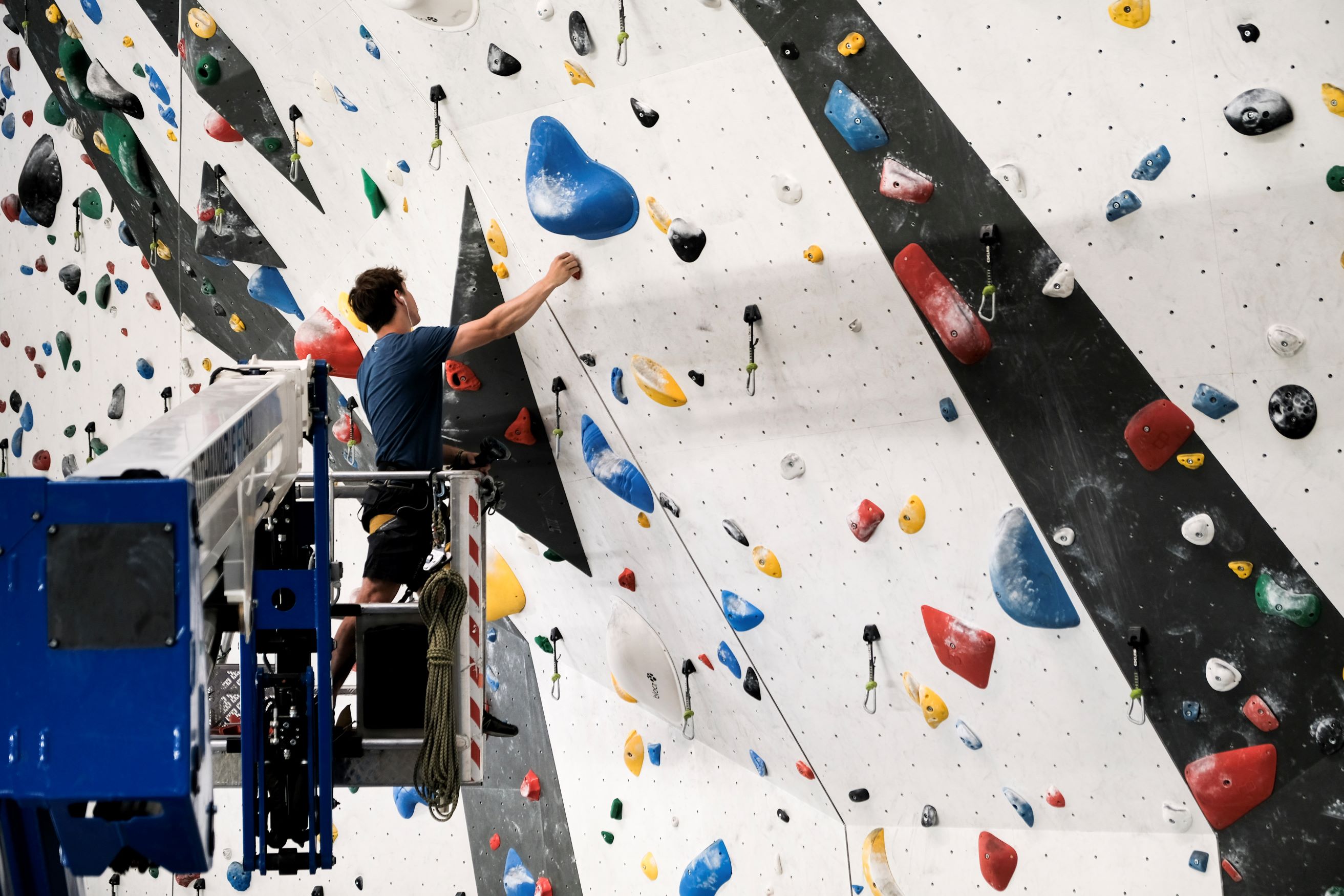 Routenbauer auf Steiger beim Schrauben indoor