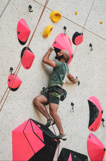Ein Parakletterer, der eine Route mit großen pink-schwarzen Griffen klettert